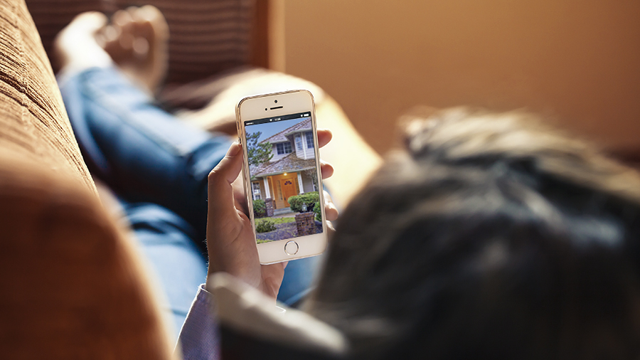 Person looking at their online home inspection report on their smartphone while laying on a couch